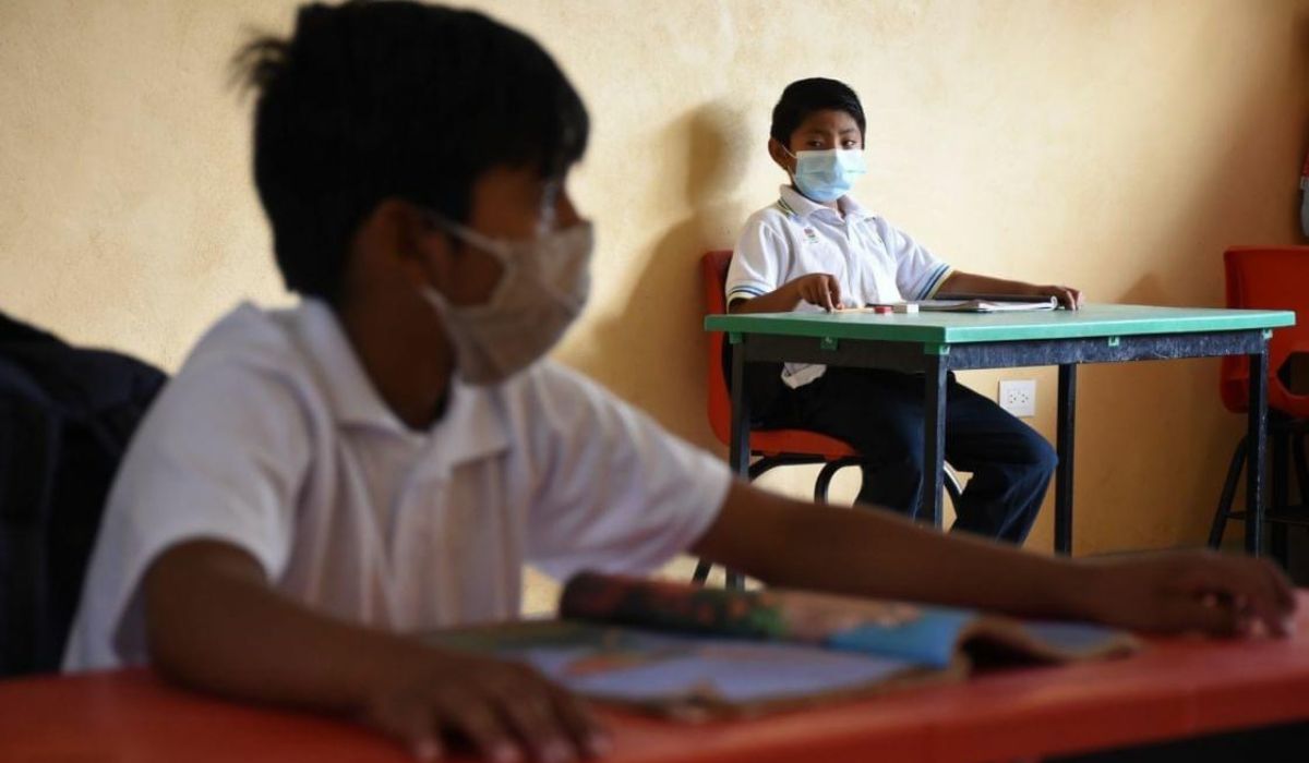 Los niños teniendo sana distancia en el salón de clases