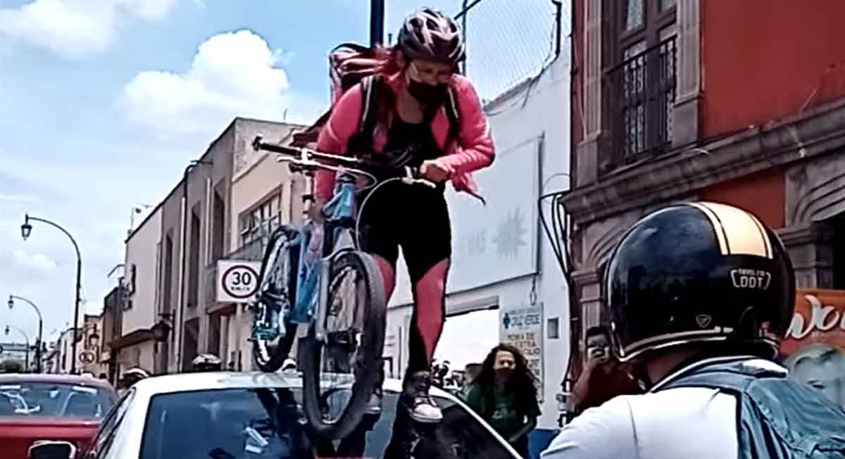 ciclistas protestan en querétaro y una se sube por encima de un auto